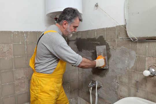 hombre colocando cemento en baño
